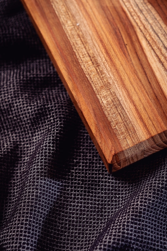 Tabla de madera con vetas naturales sobre tela oscura texturada