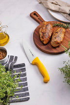 Cuchillo Tramontina con mango amarillo y hoja blanca sobre tabla de madera con pe