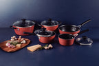 Juego de ollas y sartenes rojas con mangos negros y tapas de vidrio, acompañadas de tabla con hongos, ajo y queso