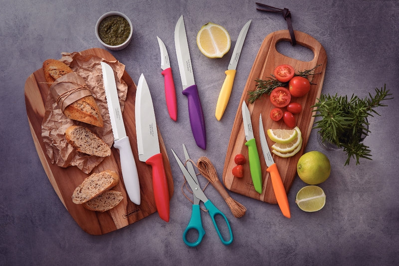 Set de cuchillos Tramontina con mangos de colores sobre tablas de madera con pan, tomates y romero