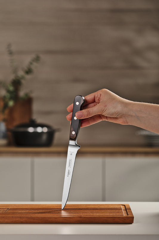 Cuchillo para deshuesar con mango de madera oscura y hoja de acero inoxidable sobre tabla de cortar de madera