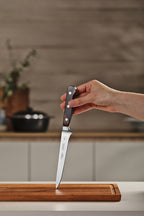 Cuchillo para deshuesar con mango de madera oscura y hoja de acero inoxidable sobre tabla de cortar de madera